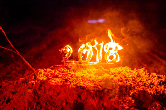 Wooden figures 2018 are burned in a flame. Conceptual photo end of the year.