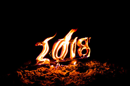 Wooden figures 2018 are burned in a flame. Conceptual photo end of the year.