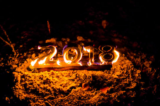 Wooden figures 2018 are burned in a flame. Conceptual photo end of the year.