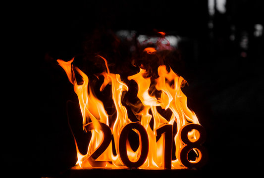 Wooden figures 2018 are burned in a flame. Conceptual photo end of the year.
