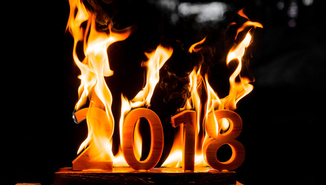Wooden figures 2018 are burned in a flame. Conceptual photo end of the year.