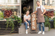 © LIGHTFIELD STUDIOS - smiling flower shop owners looking at camera on street with open signboard