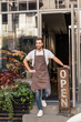 © LIGHTFIELD STUDIOS - smiling handsome florist standing on stairs of flower shop and leaning on open sign