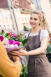 © LIGHTFIELD STUDIOS - smiling attractive florist giving beautiful bouquet of chrysanthemums to customer near flower shop