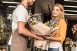 © LIGHTFIELD STUDIOS - florist giving wrapped bouquet to attractive customer at flower shop