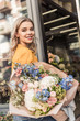 © LIGHTFIELD STUDIOS - attractive girl holding beautiful bouquet near flower shop and looking at camera