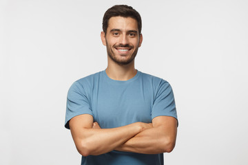 indoor portrait of young european caucasian man isolated on gray background, standing in blue t-shir
