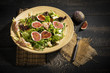 Mixed salad with figs, tomatoes, sheep cheese, grissini with ham on bamboo plate