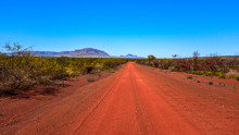 Red Dirt Road Leading To Mountain And Blue Sky