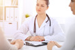 © rogerphoto - Brunette female doctor talking to patient at hospital office. Physician says about medical exams results for choosing optimal treatment. Healthcare and medicine concept