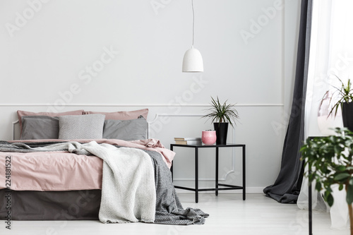 Fotografie, Obraz Warm blankets and gray pillows on a cozy double bed with dirty pink sheets by an