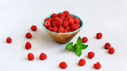 Ripe sweet raspberries in bowl light background. Close up, top view, high resolution product. Authentic lifestyle image