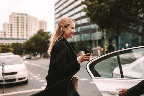 Cuadros en Lienzo Smiling businesswoman getting into a taxi