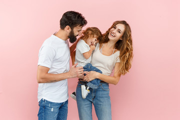 Wall Mural - A happy family on pink studio background. The father, mother and son posing together