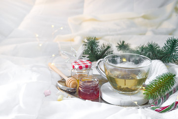 Wall Mural - tray with honey and a cup of hot tea in the bed, lazy morning, warm winter mood