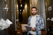 © W PRODUCTION - handsome man winemaker in a winery wine cellar during harvest season with stainless steel vats in background