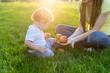 © Artem - Beautiful young modern mom playing with her cute baby son counting apples in a Sunny Park. Concept child education