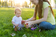 © Artem - Beautiful young modern mom playing with her cute baby son counting apples in a Sunny Park. Concept child education