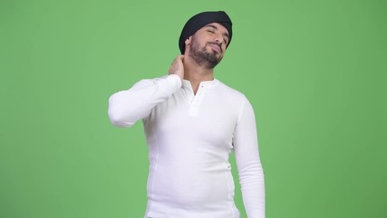 Wall Mural - Young stressed bearded Indian man having neck pain