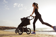 Young Mom Is Running With Stroller On The Beach.