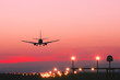 Plane landing at runway on the background of red sunset