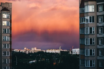 Wall Mural - scarlet bright orange sunset in front of a thunderstorm in the city