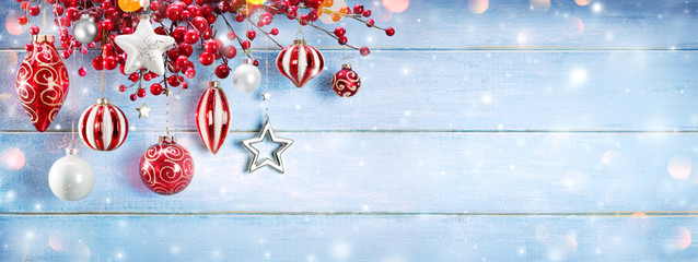 Christmas Ornaments And Berries Hanging On Snowy Wooden Plank
