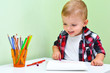 © volkonskaya - Cute little boy in a red checkered shirt laughs, he likes to study and draw in the album.