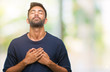 Adult hispanic man over isolated background smiling with hands on chest with closed eyes and grateful gesture on face. Health concept.