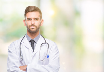 Sticker - Young handsome doctor man over isolated background skeptic and nervous, disapproving expression on face with crossed arms. Negative person.