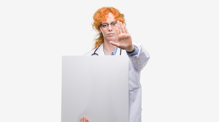 Poster - Young redhead doctor woman holding banner with open hand doing stop sign with serious and confident expression, defense gesture