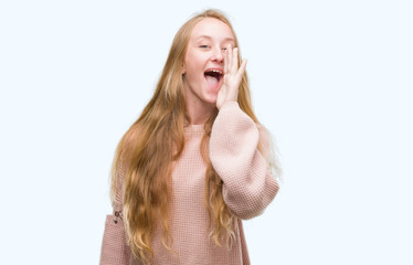 Canvas Print - Blonde teenager woman wearing pink sweater shouting and screaming loud to side with hand on mouth. Communication concept.