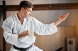 White Karate Fighter practises fight in martial arts gym