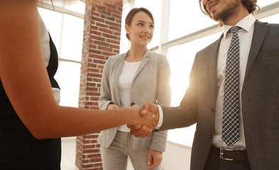 Businesspeople  shaking hands against room with large window loo