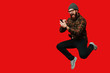 © Vulp - Bearded hipster man jumping over red background and using smartphone