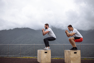 Sportsman fit male jumper doing explosive strength training jumps, crossfit fitness workout strenght power concept . Handsome strong men exercising on sky and mountain background.