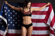 Woman bodybuilder rising freely American flag, concept of power and strength.