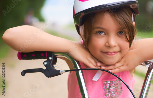 Fotografie, Obraz Close-up of a little girl's face on bike looking at camera and smiling