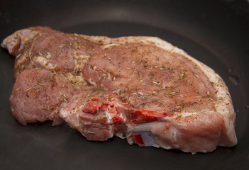 Fresh raw pork steak with spices roasting on frying pan