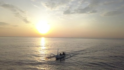 Wall Mural - backward flight over sunset ocean water with indonesian fisherman's boat on surface