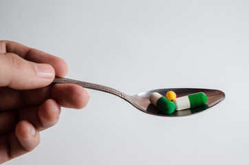 Spoon with pills on an isolated white background.