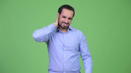 Wall Mural - Young stressed bearded Indian businessman having neck pain