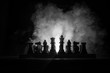 Man playing chess. Scary blurred silhouette of a person at the chessboard with chess figures. Dark toned foggy background.
