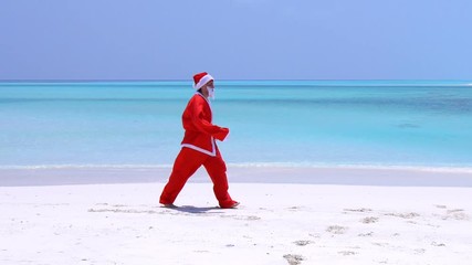 Wall Mural - Man in Santa Claus Hat dancing on sandy beach