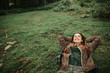 Fun trip. Portrait of beautiful girl with closed eyes resting on the grass during travelling in the forest