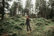 Splendid nature. Full length portrait of young woman enjoying hike in coniferous wood. She is looking away and smiling