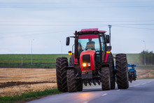 Agricultural Tractor Moving On The Asphalt Road After Working In Field
