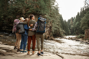 for tourists. four friends enjoying their hiking tour and standing close to each other while looking