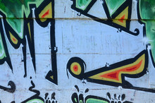 Fragment Of Graffiti Drawings. The Old Wall Decorated With Paint Stains In The Style Of Street Art Culture. Colored Background Texture In Green Tones