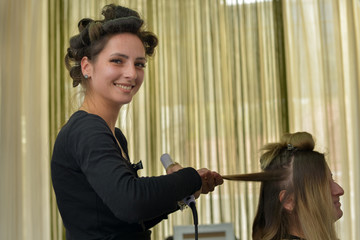 Pretty hairdresser styling hair in a beauty salon.